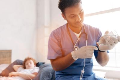 Male medical professional holding an infusion bottle while preparing a drip